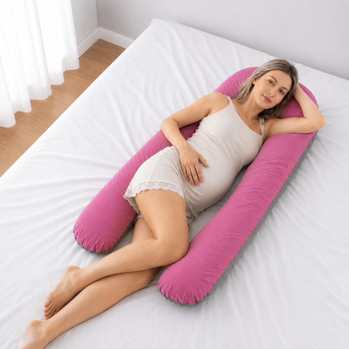 Gravid kvinna vilar i sidoläge med en rosa U-formad gravidkudde runt kroppen.