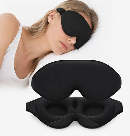 Svart sovmask i mjukt ergonomiskt material som hjälper till att blockera ljus för en mörkare och mer avslappnande sovmiljö. Visar konturerad design med urgröpningar runt ögonen för ökad komfort under sömn och vila.