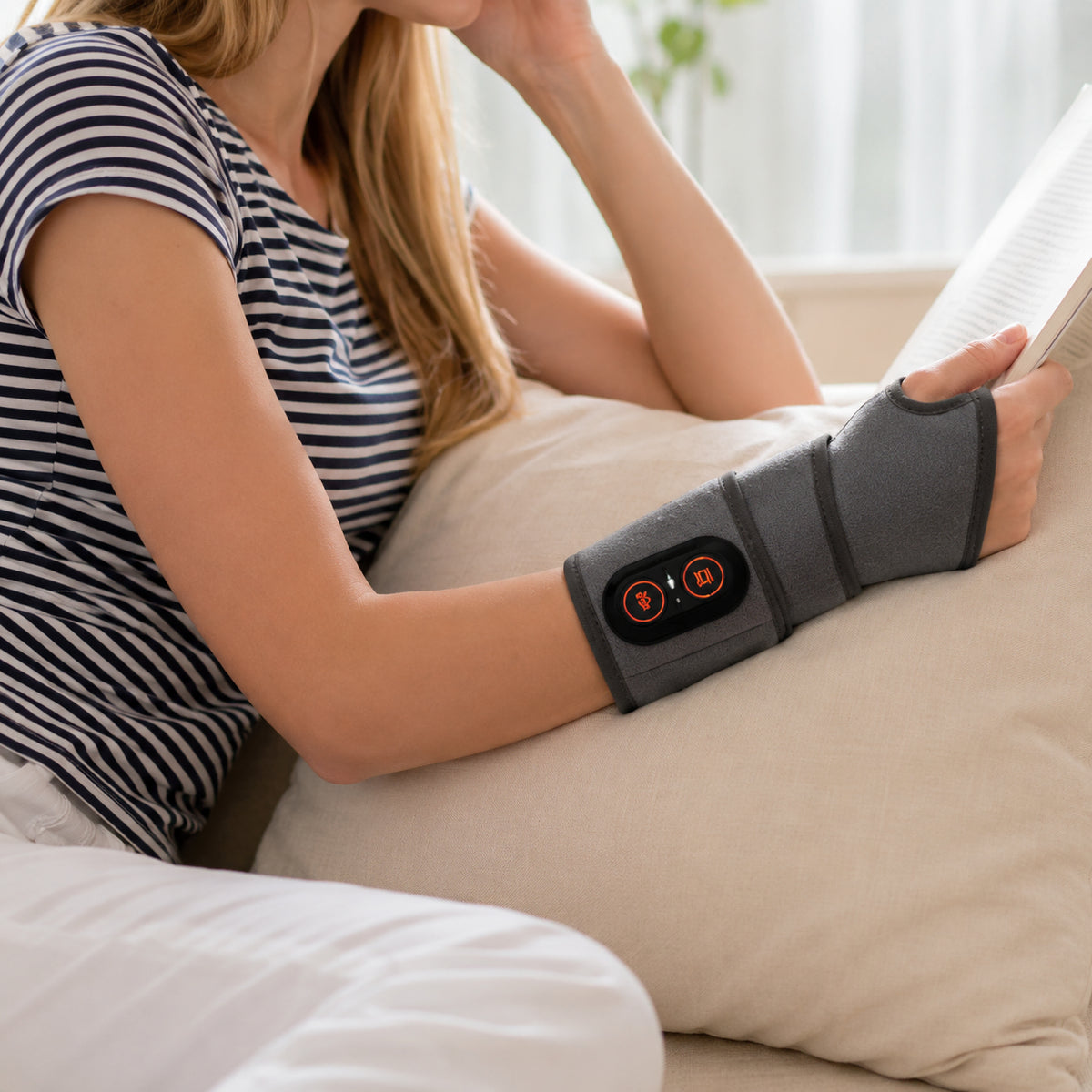 Person använder handledsband med rödljusterapi, värme och vibrationsmassage under en lugn stund hemma.