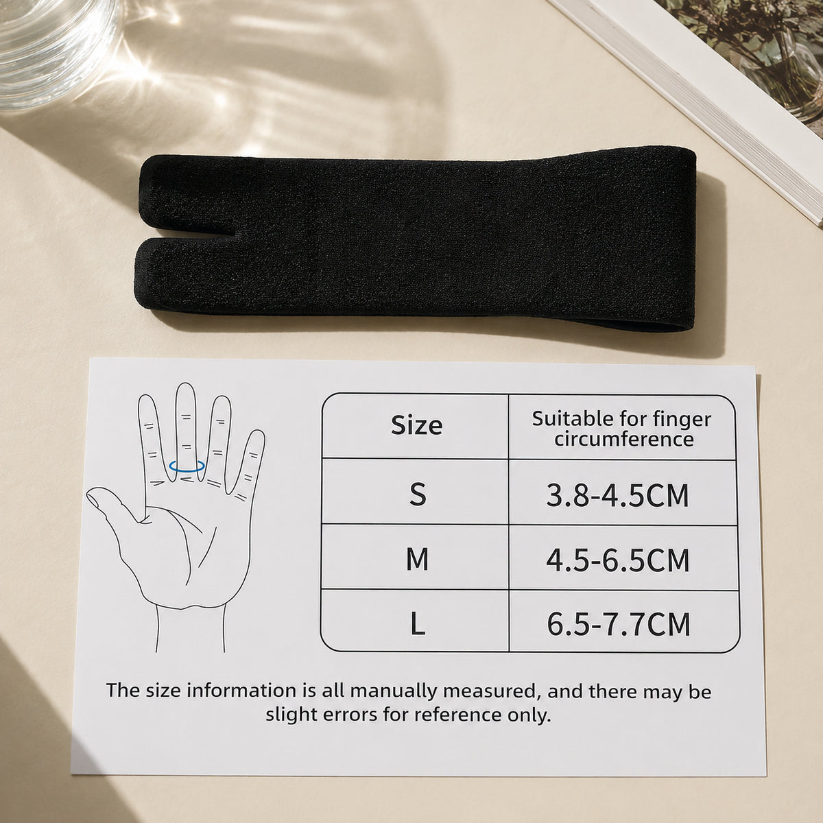 Svart justerbart fingerstöd med storleksguide för fingeromkrets i storlek S, M och L.