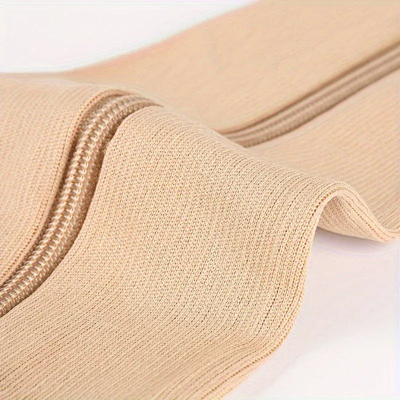 Närbild på beige stödstrumpa med sidoblixtlås och mjukt ribbat material.