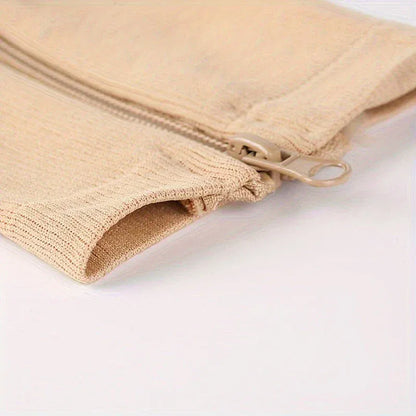 Närbild på sidoblixtlåset och det ribbade materialet på en beige stödstrumpa.